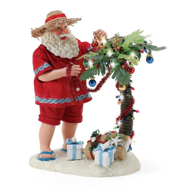 Aussie Santa in thongs and straw hat decorating palm tree